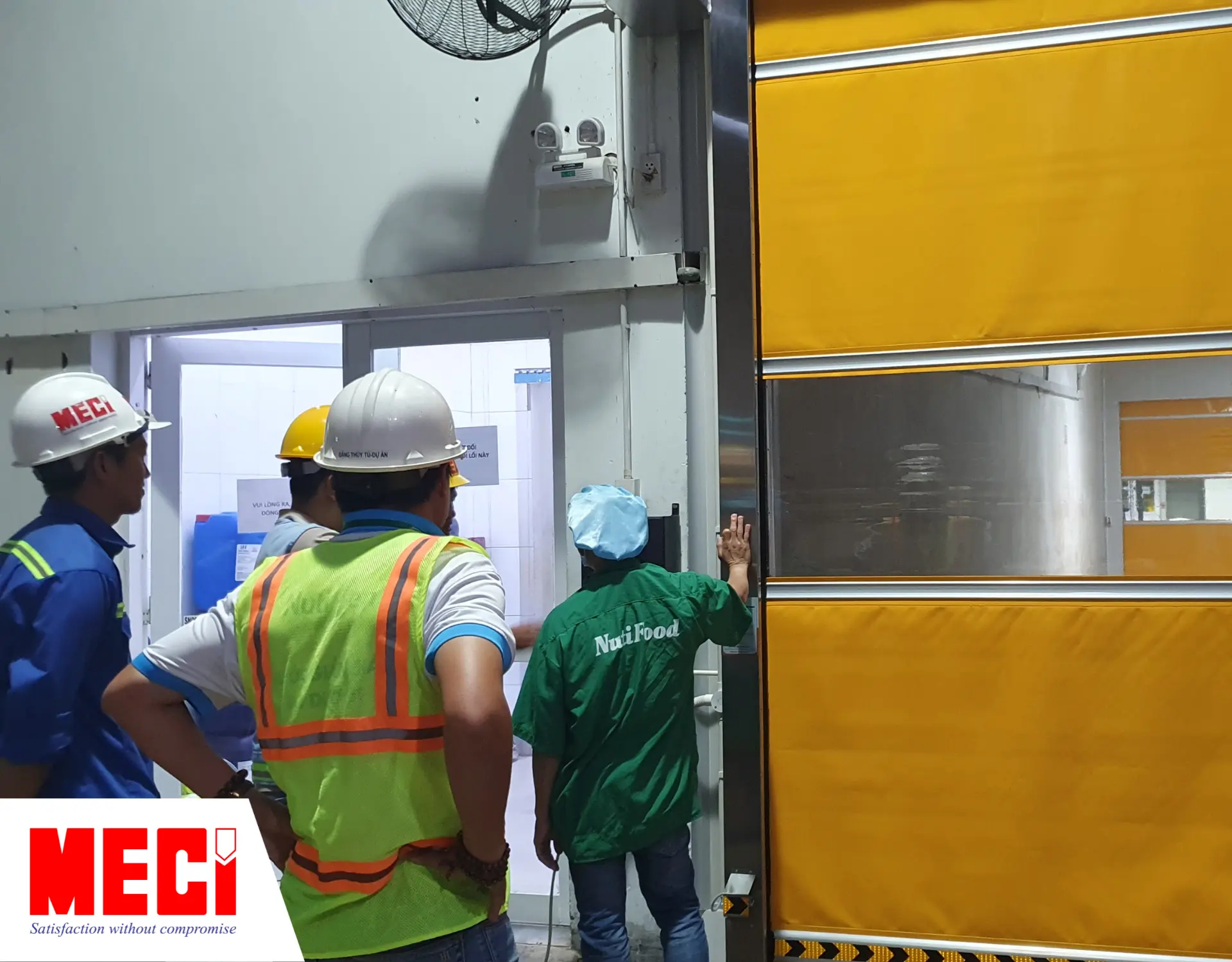 Kỹ thuật MECI đang và nhân viên Nutrifood đang thảo luận trước cửa cuốn nhanh PVC.