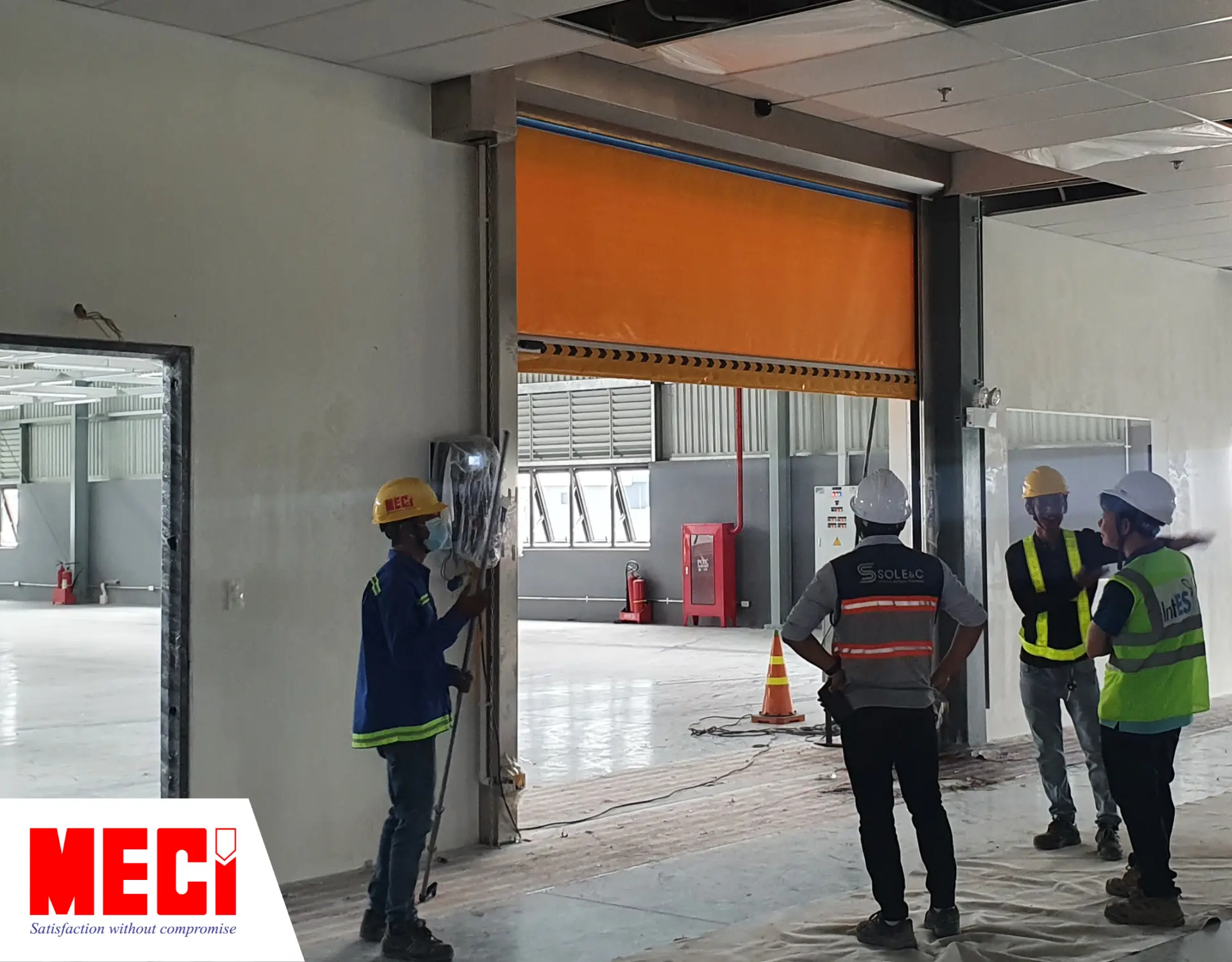 Kỹ thuật và đối tác đang thảo luận trước cửa cuốn nhanh PVC.