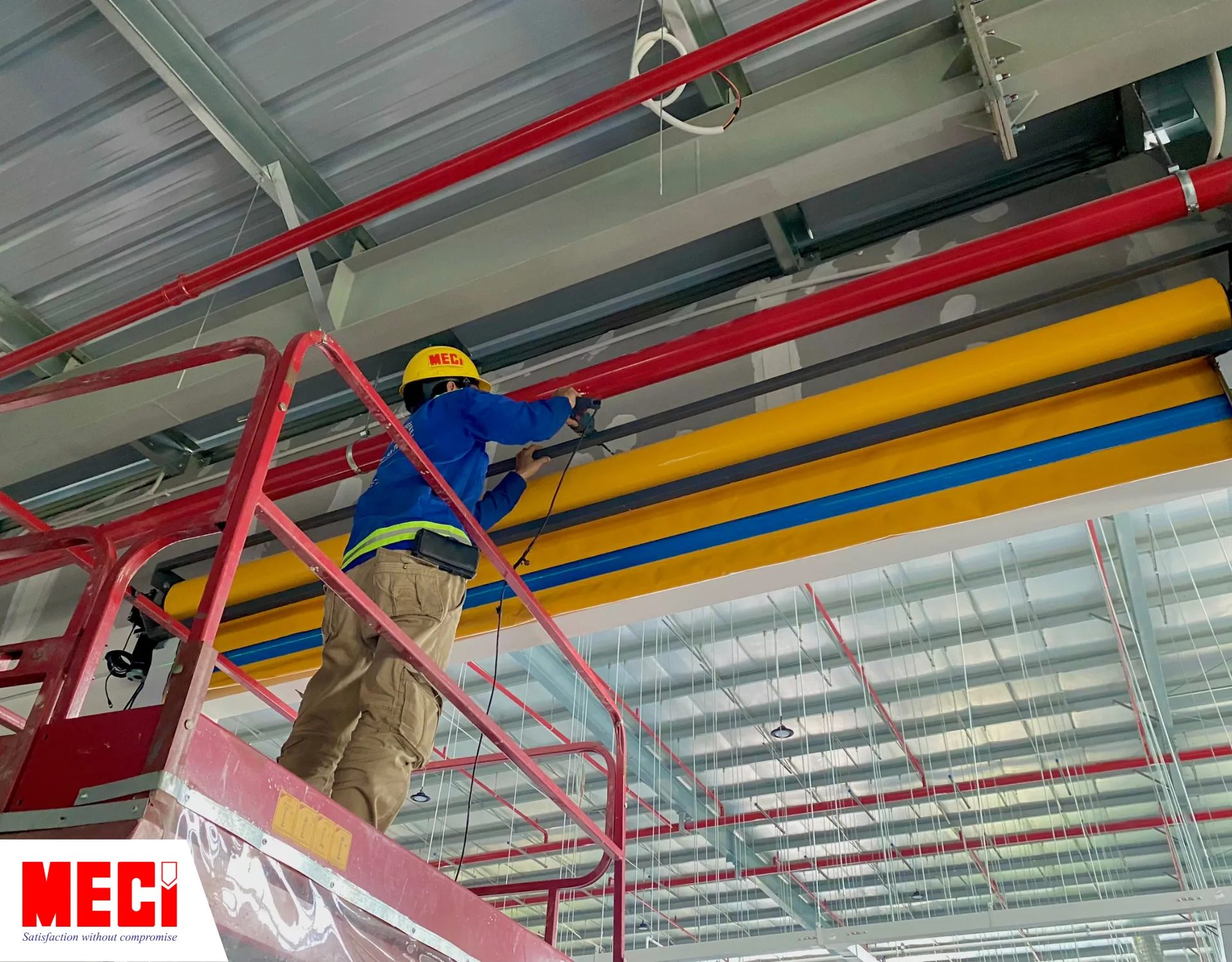 một kỹ thuật viên ở trên cái thang nâng đang sửa chữa phần lô cuốn cửa cuốn nhanh