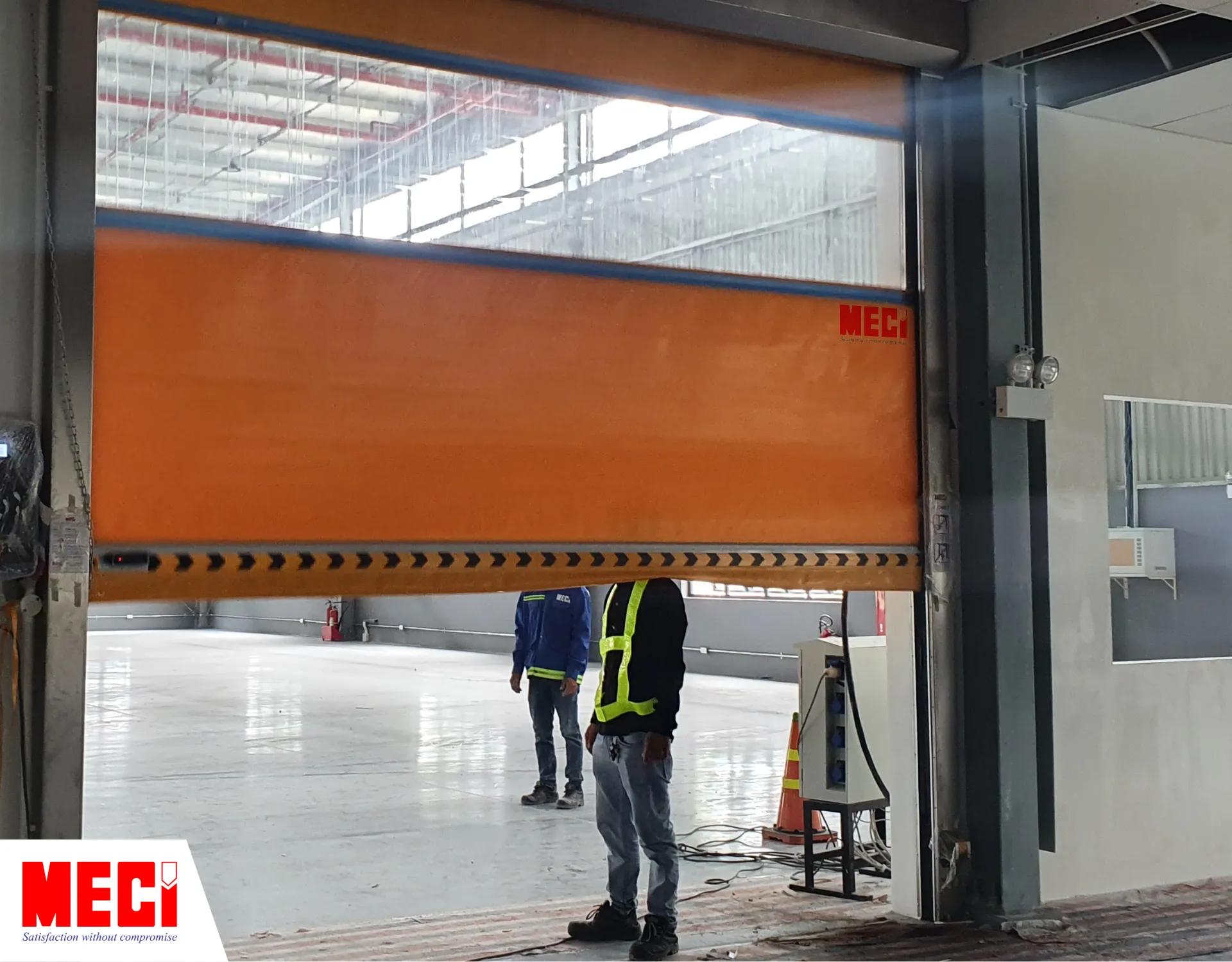 một kỹ thuật viên đang đứng chắn bên dưới cửa cuốn nhanh, cửa đóng xuống chạm vào vai anh ta