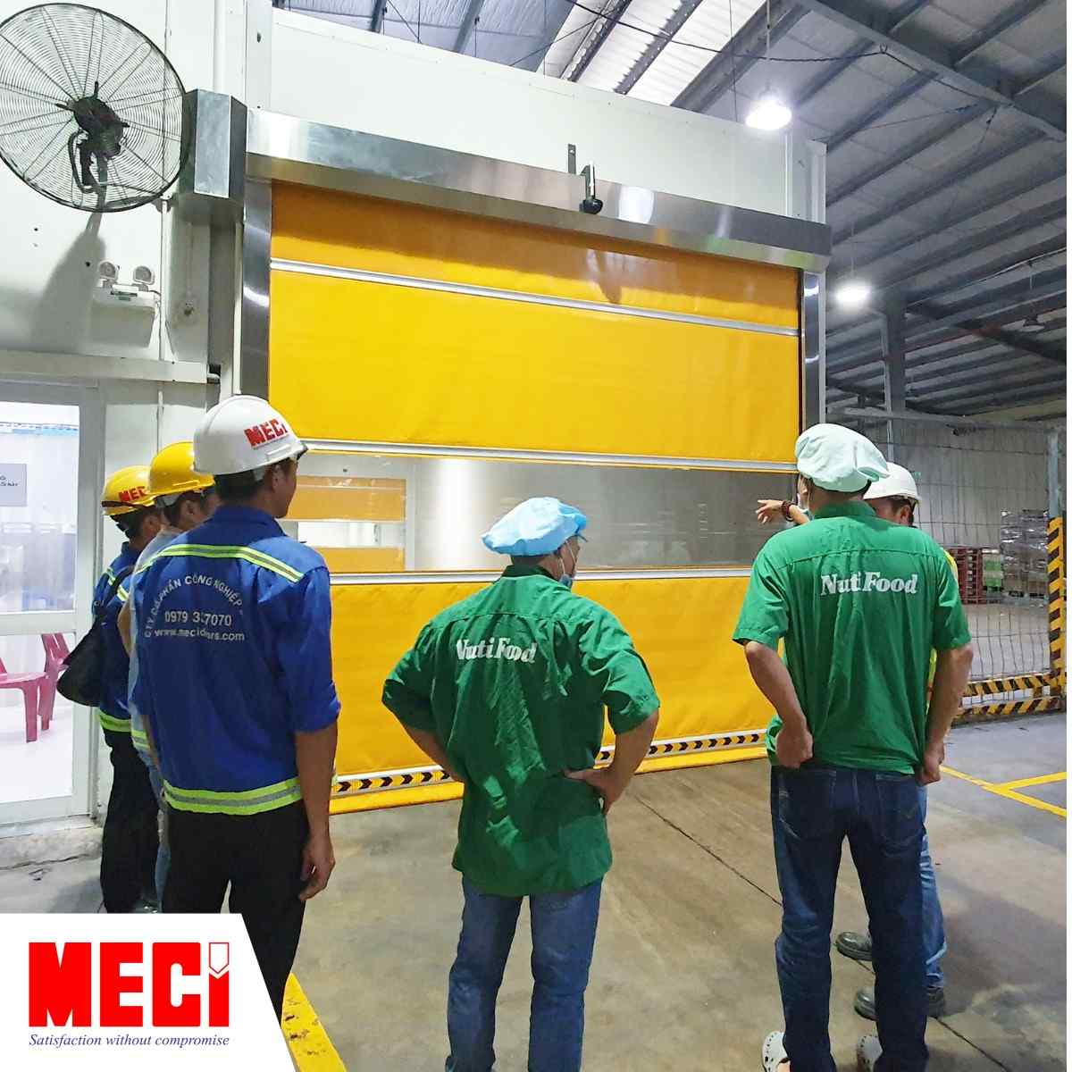 Kỹ thuật của cửa cuốn nhanh MECI sài Gòn đứng cảnh nhân viên Nutifood
