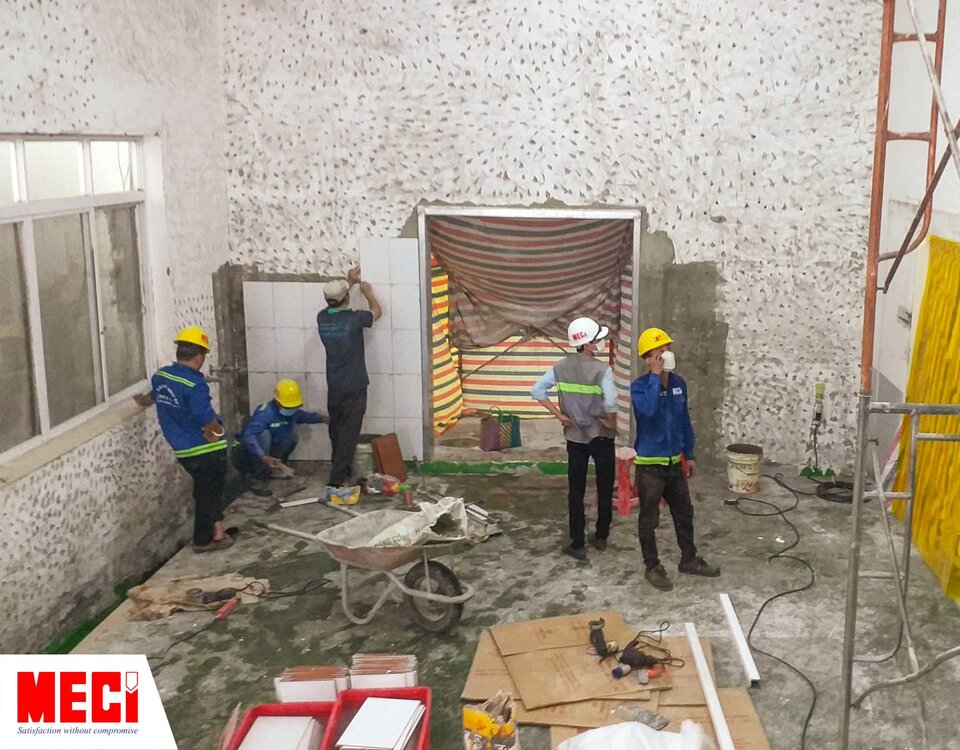 5 kỹ thuật viên bên trong căn phòng đang sửa chữa, giàn giáo và các thiết bị dụng cụ ngổn ngang