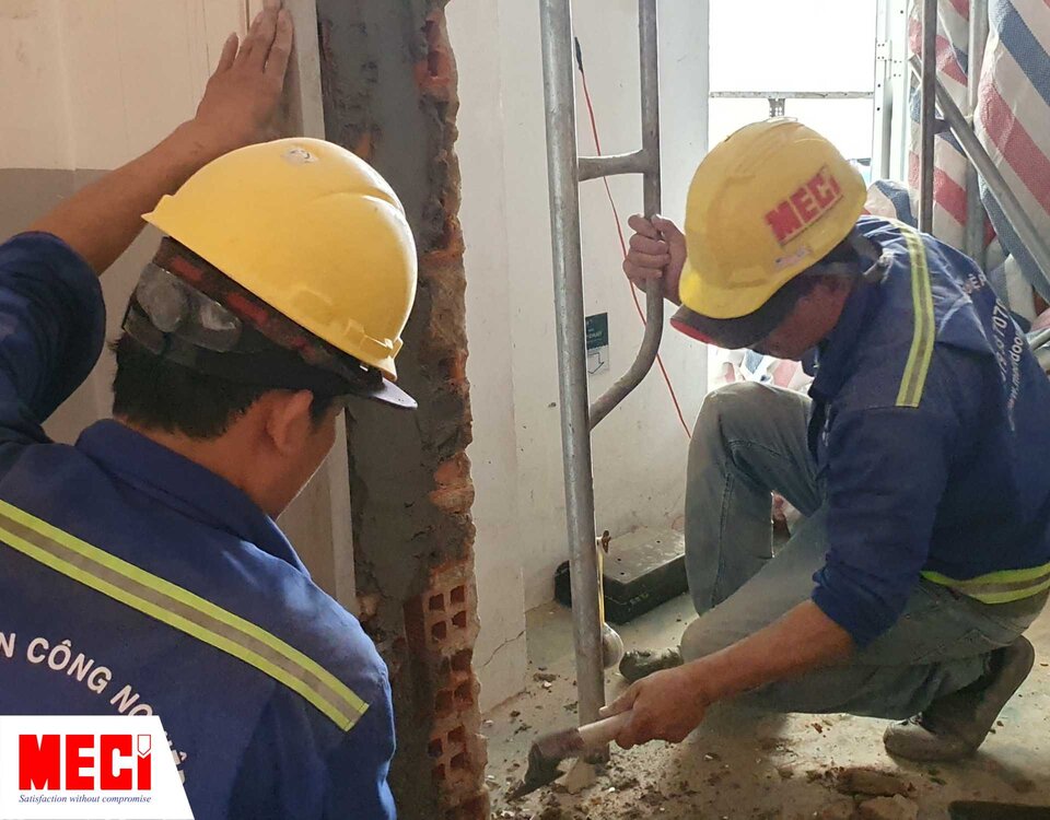 hai người đàn ông đang trét xi măng cho một vách tường