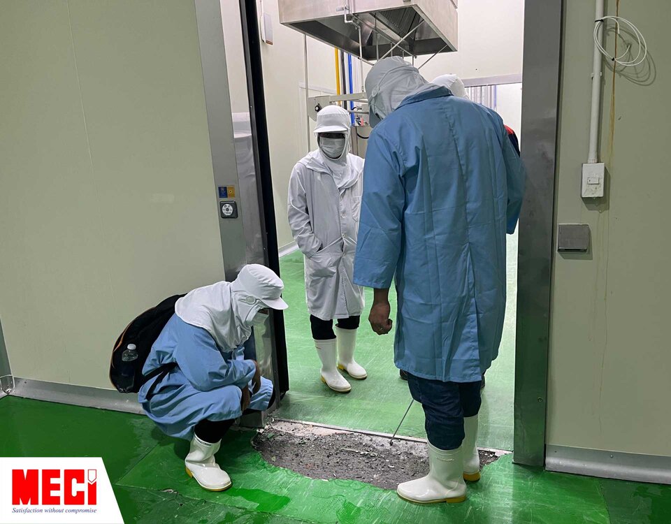 3 con người mặc trang phục trong phòng sạch đang xem xét một vết nứt lớn dưới nền epoxy