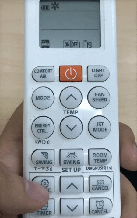 một bàn tay đang ấn remote máy lạnh