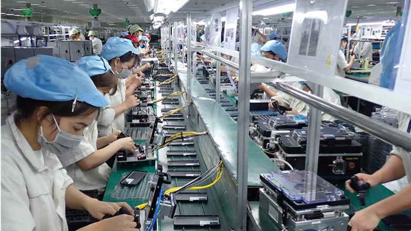 một dây chuyền sản xuất thiết bị điện tử, có nhiều công nhân đang làm việc