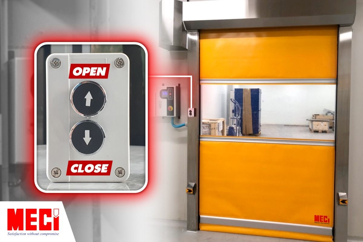 Cửa cuốn nhanh đang đóng và có một hộp nút nhấn cơ bên trái cửa