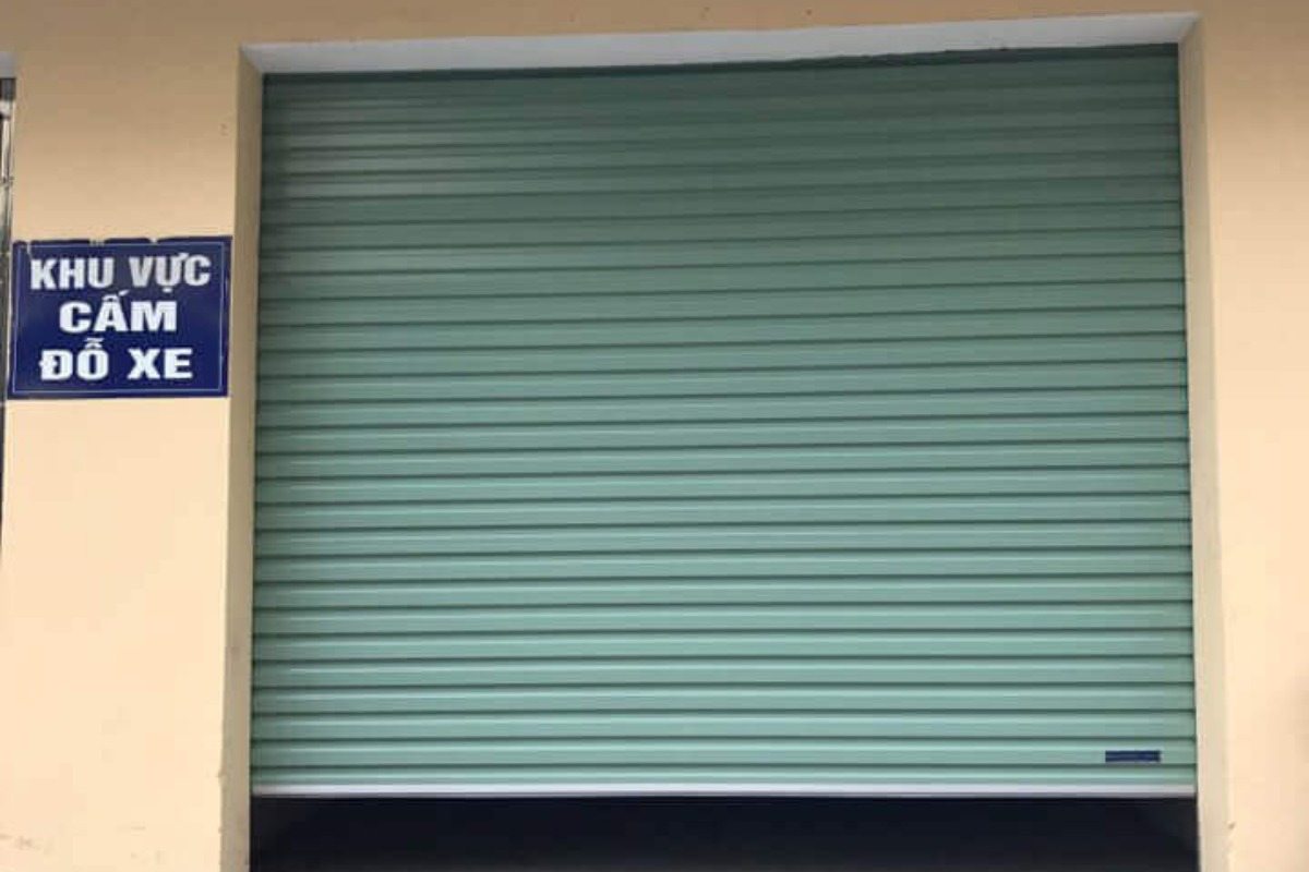 Cửa cuốn đang mở kế bên có tấm biển khu vực cấm đậu xe