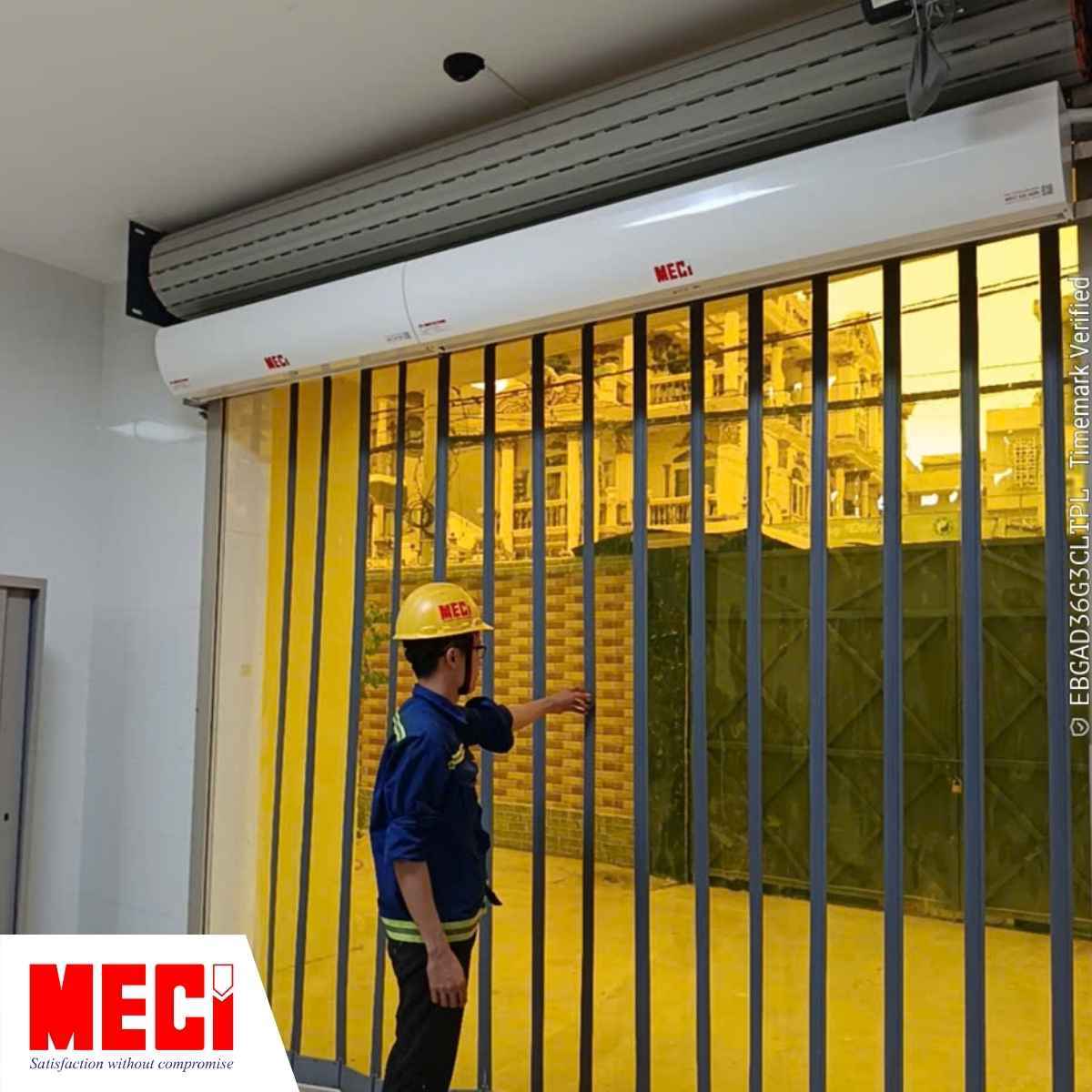 Kỹ thuật viên đang chạm vào rèm nhựa PVC, phía trên là 2 quạt cắt gió MECI