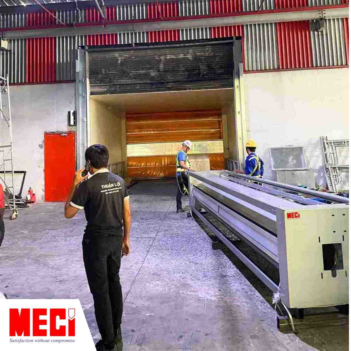 Nhân viên MECI và nhân viên Thuận Lợi đang đứng kế bên cửa cuốn nhanh nan nhôm trong nhà máy Thuận Lợi