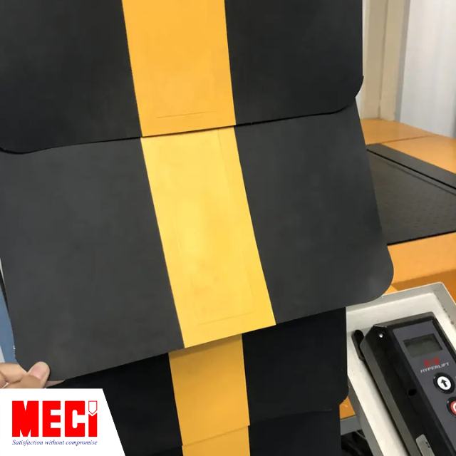 một bàn tay cầm miếng bạt nhựa UPVC màu đen có vạch kẻ vàng dọc xuống 