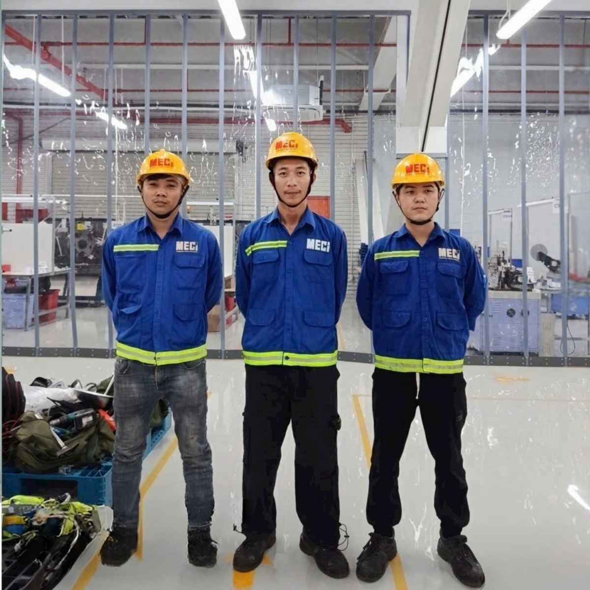 3 nhân viên kỹ thuật MECI đứng xếp hàng, phía sau là rèm nhựa nam châm ngăn lạnh