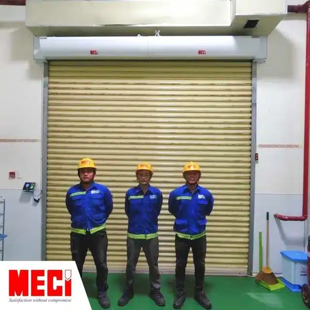 Ba anh kỹ thuật đứng trước cửa kim loại và hai quạt cắt gió MECI