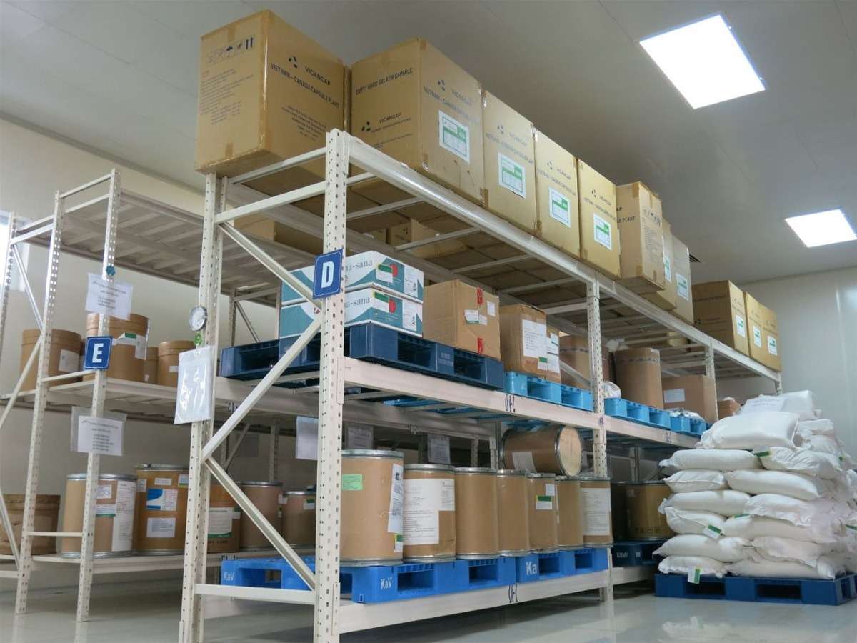 khung cảnh bên trong nhà khi, có 2 kệ hàng to, bên trên để rất nhiều thùng hàng chứa nguyên liệu đầu vào