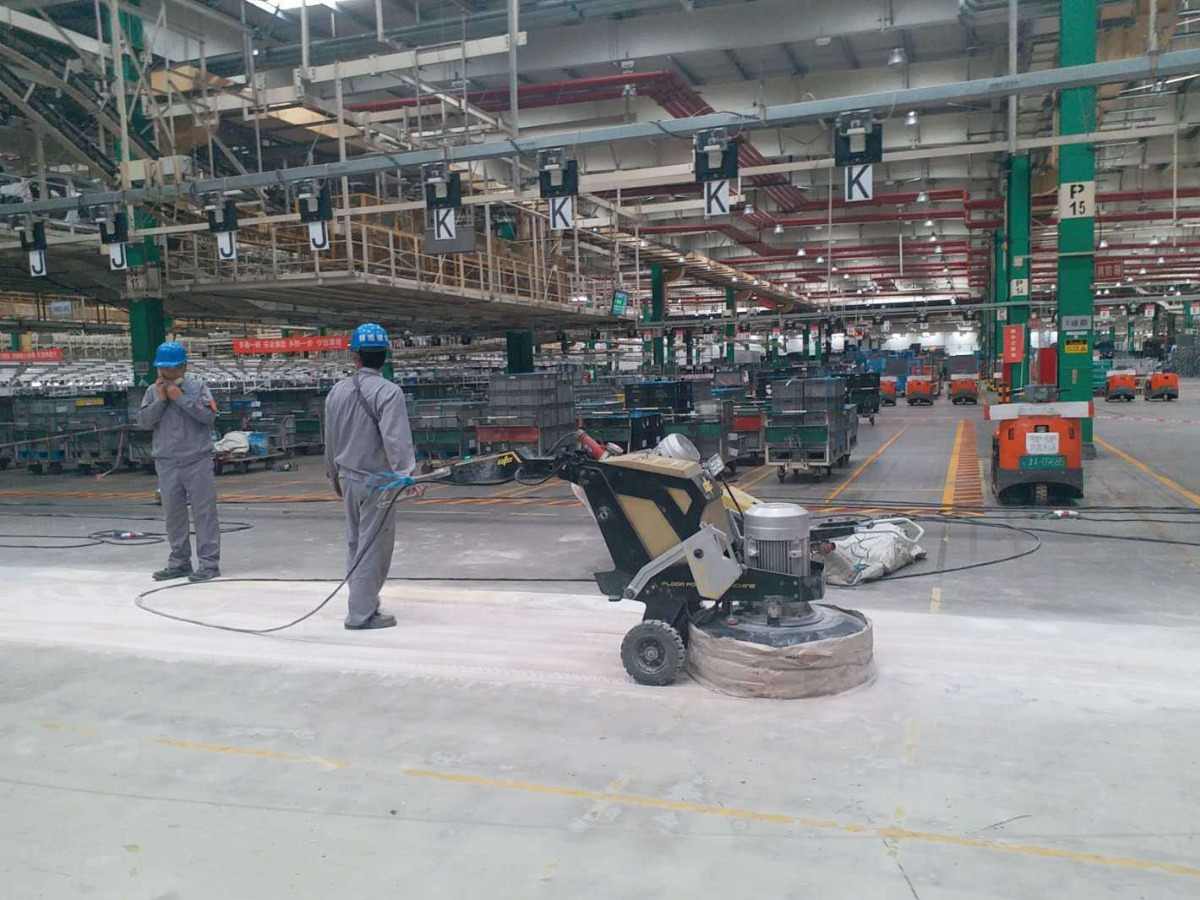 khung cảnh bên trong nhà máy, có 2 nhân viên đang dùng máy hút bụi công nghiệp để vệ sinh nhà xưởng