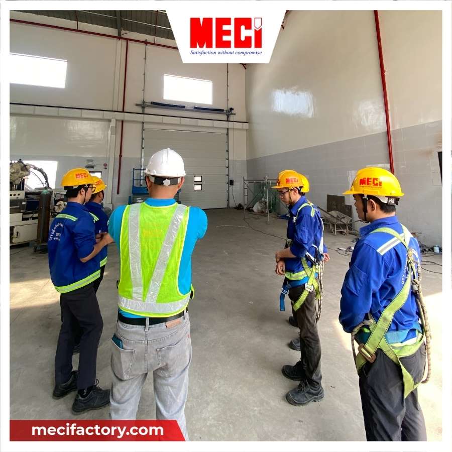 Đội ngũ kỹ thuật của MECI đang đứng nhìn về phía cửa trượt trần và bàn bạc 